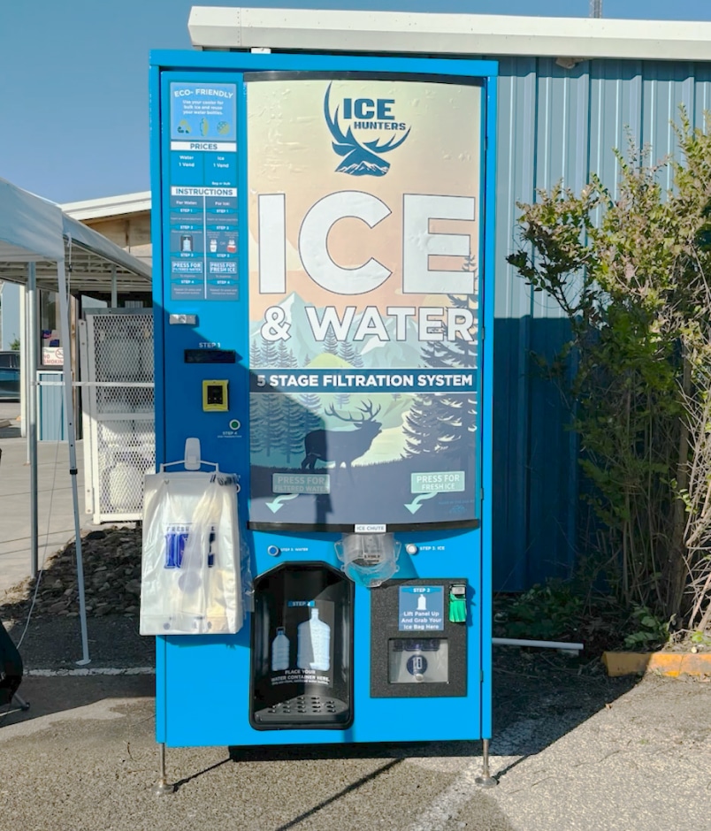 A custom branded Ice Hunters Ice and Water vending machine outside of an industrial location